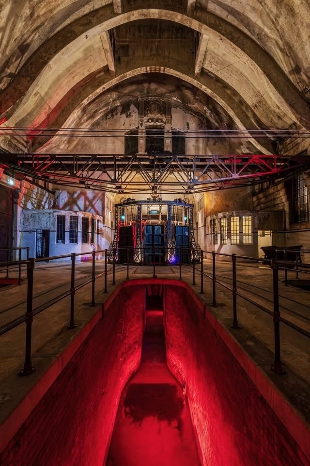 Rot beleuchteter Klärkanal mit historischen technischen Einbauten
